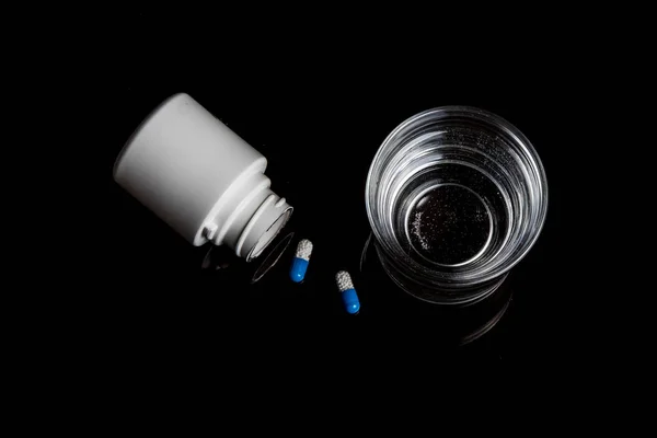 Píldoras médicas aisladas sobre un fondo negro — Foto de Stock