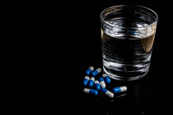 Pillole mediche isolate su uno sfondo nero — Foto Stock