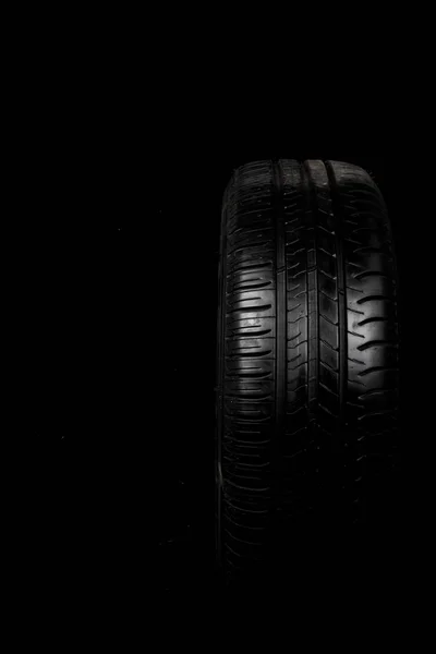 Car tyre isolated on a black background — Stock Photo, Image