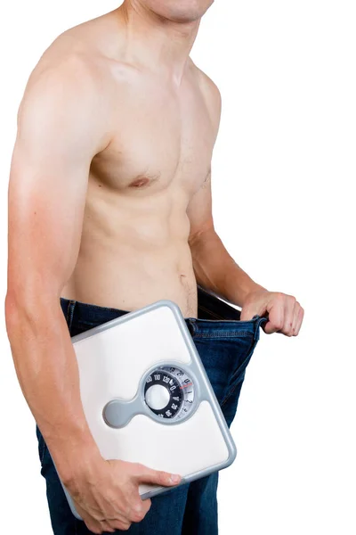 一个体重减轻的概念显示一个肌肉发达的年轻男子拿着装有浴室秤的袋装 — 图库照片