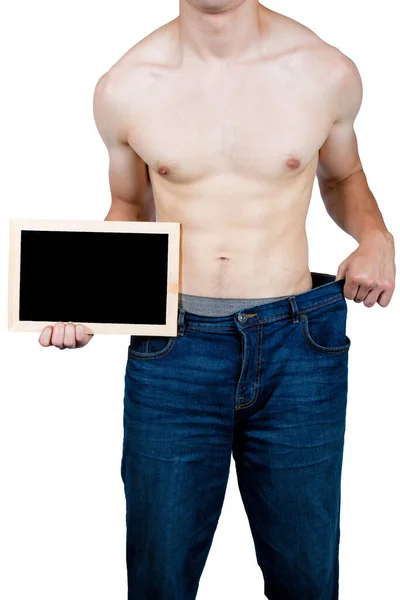 一个肌肉发达的年轻男子拿着袋装衣服 拿着一块写有标语的黑板 — 图库照片
