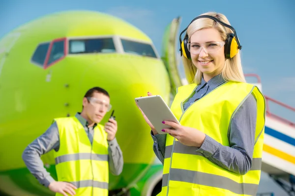 Trabajadores del aeropuerto con el avión en el fondo — Foto de Stock