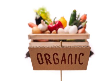 Ahşap kırsal kutuda organik sebzeler ve karton kare etiketli üst toprak. Fiyat etiketi, hediye etiketi, satış etiketi, beyaz arkaplanda izole edilmiş etiket