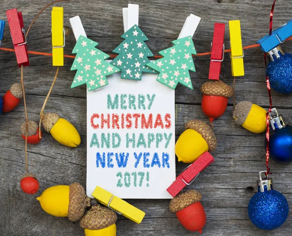 Веселий різдвяний і щасливий новий рік 2017 листівка фон з ручної роботи гірлянди з кольорових жолудів, декоративних іграшок і дерев'яної ялинки . — стокове фото