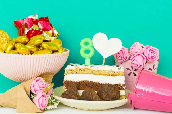 Επιδόρπιο και καραμέλες από σοκολάτα σε ένα πιάτο με ένα κερί 8, κανένας σε σχήμα καρδιάς για κείμενο, ένα μπουκέτο λουλούδια σε ένα κουβά. Ευχετήρια κάρτα Happy γυναικών μέρα στις οκτώ Μαρτίου — Φωτογραφία Αρχείου