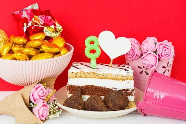 Επιδόρπιο και καραμέλες από σοκολάτα σε ένα πιάτο με ένα κερί 8, κανένας σε σχήμα καρδιάς για κείμενο, ένα μπουκέτο λουλούδια σε ένα κουβά. Ευχετήρια κάρτα Happy γυναικών μέρα στις οκτώ Μαρτίου — Φωτογραφία Αρχείου
