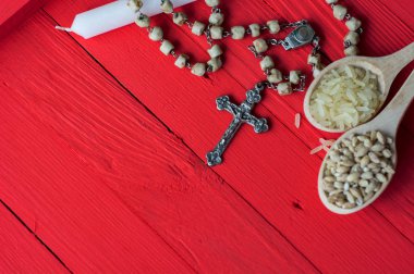 Beyaz Mum, İncil ve pirinç ve bir tahta kaşık - eski masada parlak kırmızı buğday tohumları Hıristiyan haç kolye gümüş. Büyük oruç - tonlu görüntü başında bir sembolü olarak 