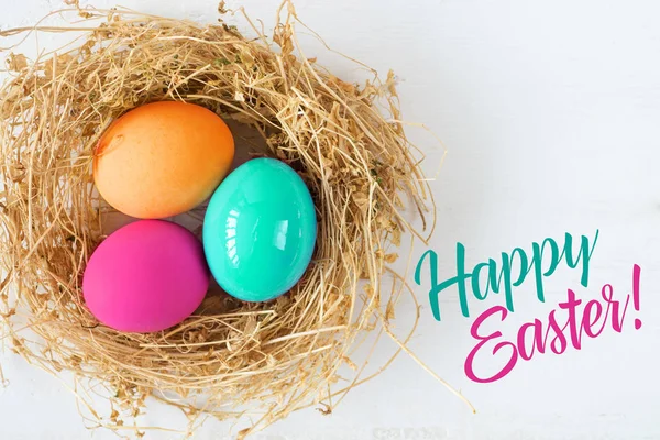 Renkli yumurta yuvada ahşap arka plan, seçici odak resim üzerinde. Mutlu Paskalya kartı - metin için yer — Stok fotoğraf