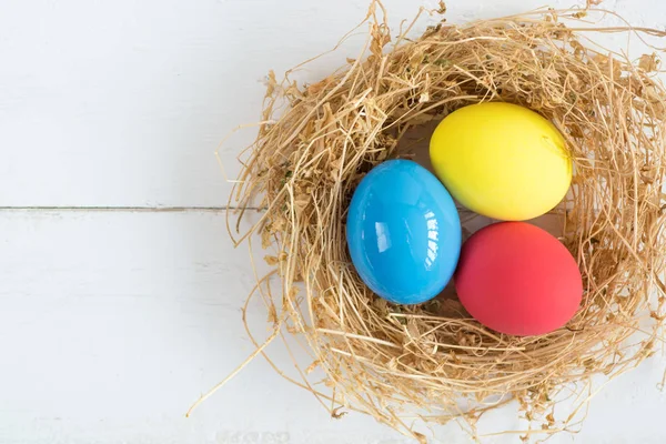 A színes tojásokat fészekben fából készült háttér, szelektív fókusz a kép. Boldog húsvéti üdvözlőlap - hely a szöveg — Stock Fotó