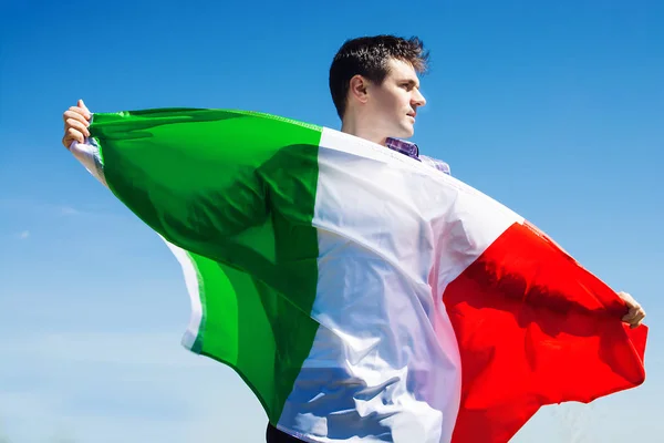 Młody człowiek trzyma włoskiej flagi przeciw błękitne niebo. stonowanych obrazów — Zdjęcie stockowe