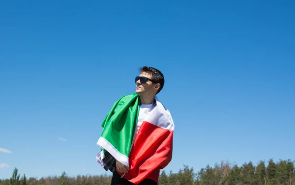 Mladý muž drží italské vlajky proti modré obloze s textem den republiky Itálie Live. tónovaný obrázek — Stock fotografie