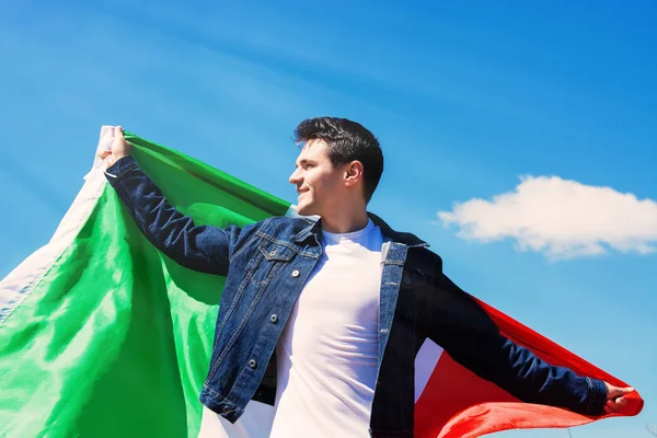 Mladý muž drží italské vlajky proti modré obloze s textem den republiky Itálie Live. tónovaný obrázek — Stock fotografie