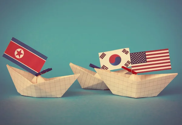 미국과 북한의 국기와 함께 종이 배. 일본 바다, 개념 선적 또는 자유 무역 계약 및 회원 충돌 — 스톡 사진