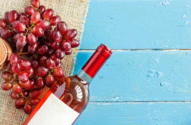 Demet taze olgun kırmızı üzüm ve mavi ahşap dokusal yüzeyi gül şarabı. metin reklam alanı