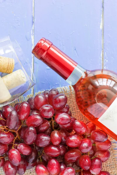 Demet taze olgun kırmızı üzüm ve mavi ahşap dokusal yüzeyi gül şarabı. metin reklam alanı