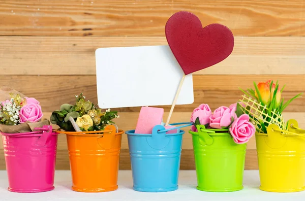 Flores em pails coloridos e uma nota na forma de um coração, espaço para texto — Fotografia de Stock