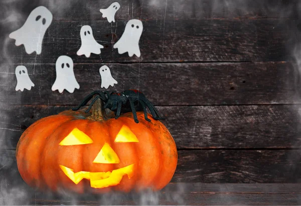 Spooky Halloween pumpkin head jack lantern surrounded by ghosts in the fog on wooden background