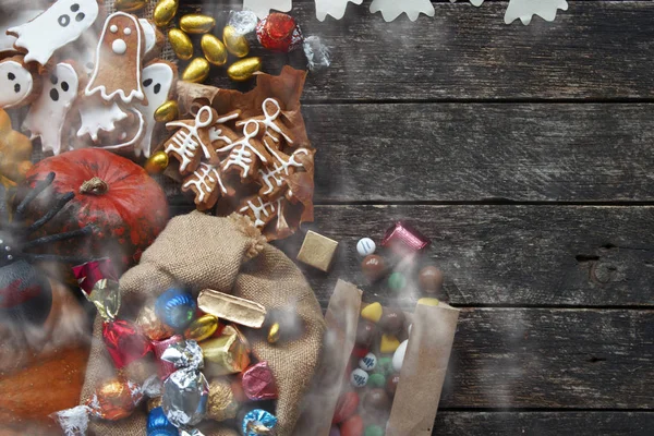 Šťastný Halloween karta. Legrační lahodný zázvorový cookie tvar ducha a kostra, pytel sladkostí a cukrovinky s dýní a sladkosti. — Stock fotografie