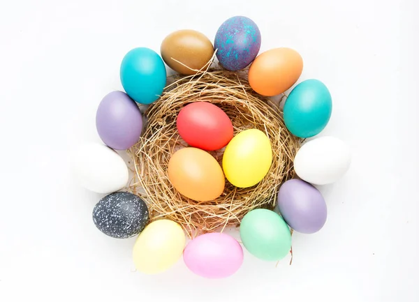 Multi-colored Easter eggs in nest on wooden background, selective focus image. Happy Easter card