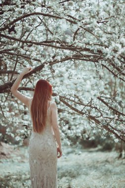 Bahar bahçe uzun ışık elbiseli kızıl saçlı kız.