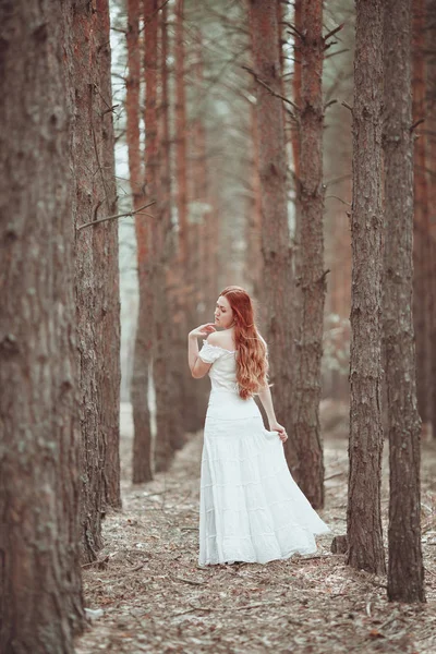 Ragazza zenzero in abito bianco a piedi nella pineta . — Foto Stock