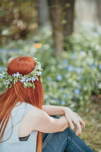 Girl sitting on the periwinkle field. — Stock Photo, Image