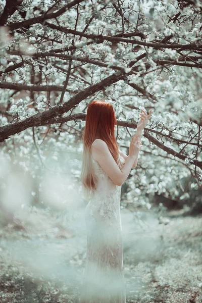 Redhead dziewczyna w długie, jasne sukienka w spring garden. — Zdjęcie stockowe