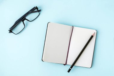 Mavi ofis Masaları boş not defteri, kalem, gözlük ile. Metin için yer kopyalayın. Düz yatıyordu. Üstten Görünüm.
