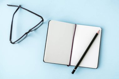 Mavi ofis Masaları boş not defteri, kalem, gözlük ile. Metin için yer kopyalayın. Düz yatıyordu. Üstten Görünüm.