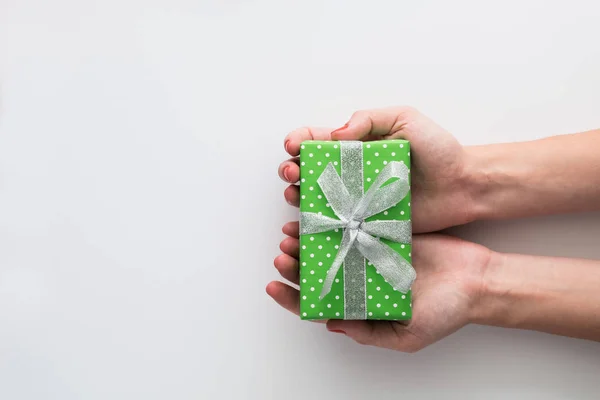 Manos de mujer sosteniendo caja de regalo verde aislado sobre fondo blanco. Vista superior, cama plana. Espacio de copia . — Foto de Stock