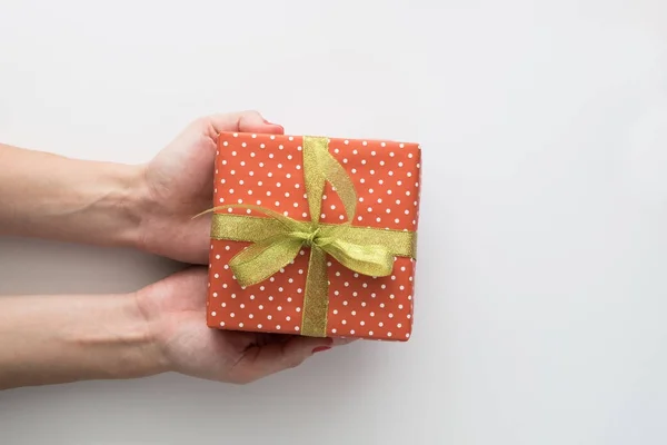 Manos de mujer sosteniendo caja de regalo roja aislada sobre fondo blanco. Vista superior, cama plana. Espacio de copia . — Foto de Stock