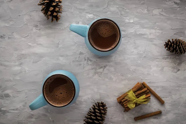 Christmas and New Year cozy holiday composition with cinnamon, pine cone, mugs with cocoa or chocolate on the gray concrete background. Flat lay, top view. — Stock Photo, Image