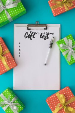Noel ve yılbaşı tatil listesi yapmak için not defteri, kalem, hediye kutuları üzerinde mavi arka plan ile. Kadar alay et. Düz yatıyordu, en iyi görünümü.
