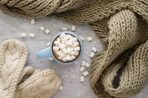 Komposisi liburan Natal dan Tahun Baru yang nyaman dengan syal, sarung tangan, cangkir dengan kakao atau coklat, marshmallow dengan latar belakang beton abu-abu. Letak datar, tilikan atas . — Stok Foto