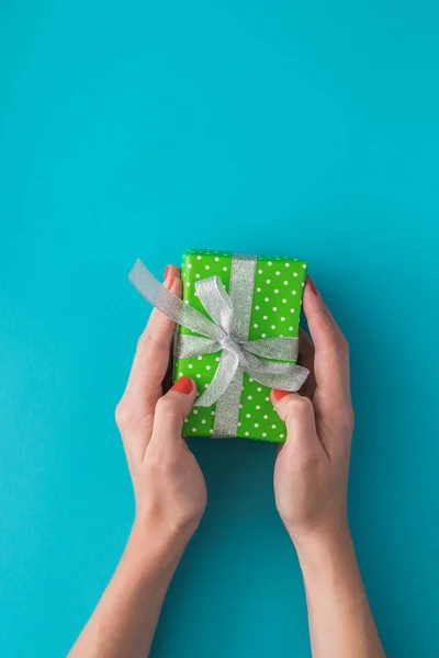 Mujer mano sosteniendo caja de regalo verde aislado en el fondo azul. Vista superior, cama plana. Espacio de copia . — Foto de Stock