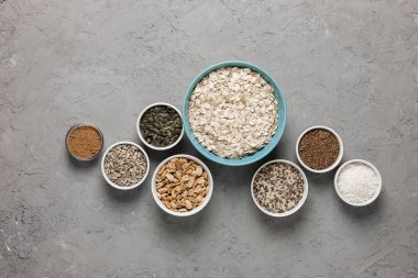 Ev yapımı granola yemek pişirmek için malzemeler: yulaf ezmesi, Kuru üzüm, Hindistan cevizi cips, tatlım, fıstık, kakao, yaban mersini, bitkisel yağ, keten, susam, kabak ve ayçiçeği tohumu. Beton arka plan. Üstten Görünüm.