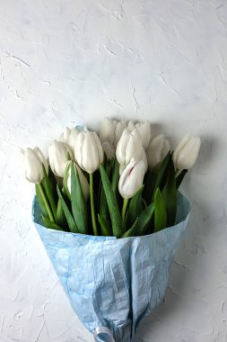 Paket kağıdı bir gri beton zemin üzerinde Mavi Beyaz Lale buketi. Üstten Görünüm. Düz yatıyordu. Paskalya, anneler günü ve bahar tatil kartpostal.