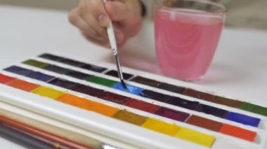 Tanınmayan kadın bir fırça ile Paskalya yumurtaları boyar. Bir bardak su ve yumurta bir kase tablodur. Tatil için hazırlanıyor.