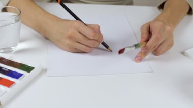 Tanınmayan kadın kalem eskiz kağıt Paskalya kartı üzerinde çizer. Bir palet boya ve bir bardak su ile geçerli.