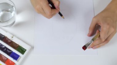 Tanınmayan kadın kalem eskiz kağıt Paskalya kartı üzerinde çizer. Bir palet boya ve bir bardak su ile geçerli.