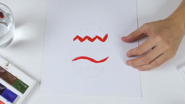 Неузнаваемая женщина рисует эскиз с яркими красками на бумаге для пасхальной открытки. На столе - палитра красок и стакан воды . — стоковое видео