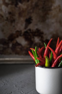 Gri arka plan üzerinde beyaz Kupası'nda kırmızı küçük pul biber. Seçici odak.