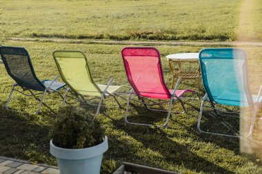 Dört renkli güneşlik dışarıda yeşil çimlerin üzerinde duruyor. Sessiz ve huzurlu bir yerde açık hava eğlencesi kavramı..