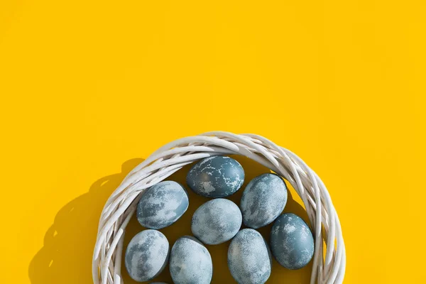 Uova di Pasqua blu strutturate colorate in un nido o corona su uno sfondo festivo giallo brillante. Concetto vacanza primaverile. Copyspace. Piatto. Vista dall'alto . — Foto Stock