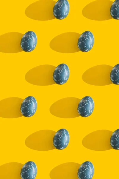 Huevos de Pascua de color azul texturizado sobre un fondo de vacaciones amarillo brillante. Concepto vacaciones de primavera. Copyspace. Acostado. Vista superior. Luz dura. Sombra larga . — Foto de Stock