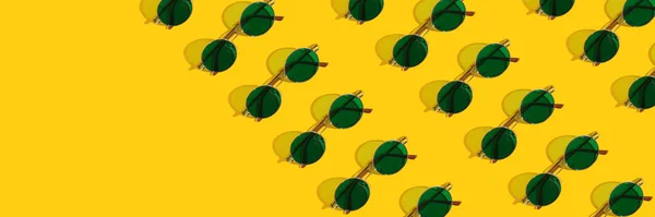 Patrón de estandarte de gafas de sol amarillas redondas verdes sobre un fondo amarillo brillante con una sombra dura. Protección solar en verano . — Foto de Stock