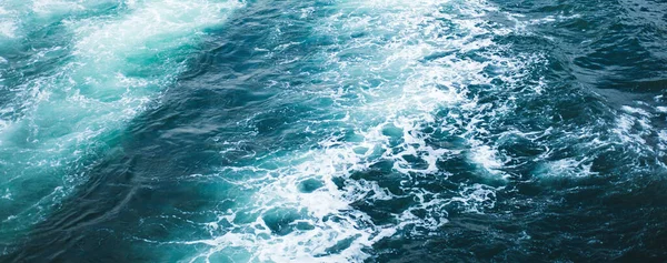 Mar ou oceano ondas textura superficial. Verão abstrato fundo de água azul com salpicos de espuma do mar . — Fotografia de Stock