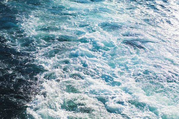 海や海の波の表面のテクスチャ。概要海泡の飛沫を伴う夏の青い水の背景. — ストック写真