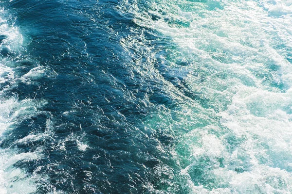 Mar ou oceano ondas textura superficial. Verão abstrato fundo de água azul com salpicos de espuma do mar . — Fotografia de Stock