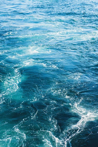 Havs- eller havsvågor ytstruktur. Abstrakt sommar blått vatten bakgrund med stänk av havsskum. — Stockfoto